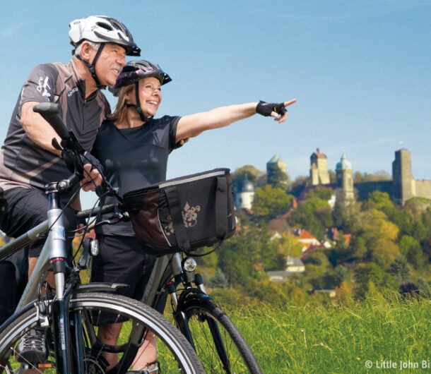 Ehepaar in Rad-Outfit auf dem Radweg bei Stolpen, im Hintergrund die Burg Stolpen